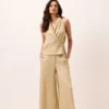 Calça pantalona areia em tecido canelado leve, cintura média/alta, cós com zíper e gancho, bolsos laterais e perna ampla longa