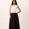 Saia midi preta em rami, corte rodado evasê, cintura alta e barra ampla, usada com blusa off-white de um ombro só em estúdio