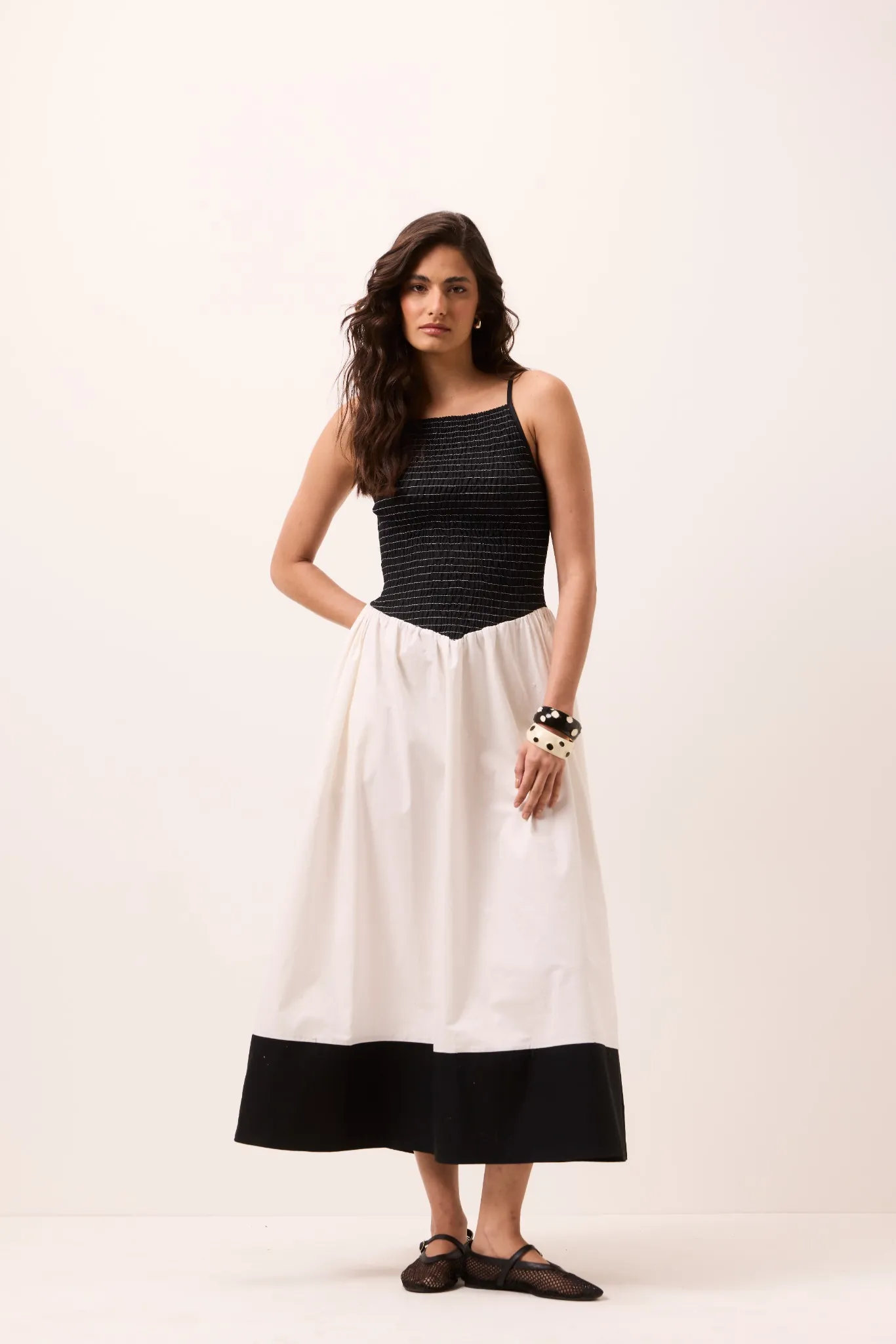 Vestido midi preto e branco sem mangas com busto em lastex, cintura em bico e saia rodada com faixa preta na barra
