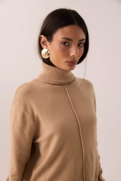 Blusa de tricot camelo com gola alta canelada e costura frontal, vista no corpo em estúdio