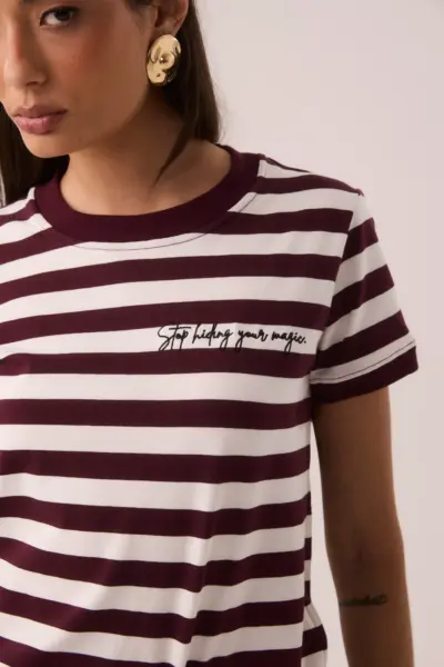 Camiseta listrada vinho e branca com gola redonda, mangas curtas e bordado 'Stop Hiding Your Magic' no peito
